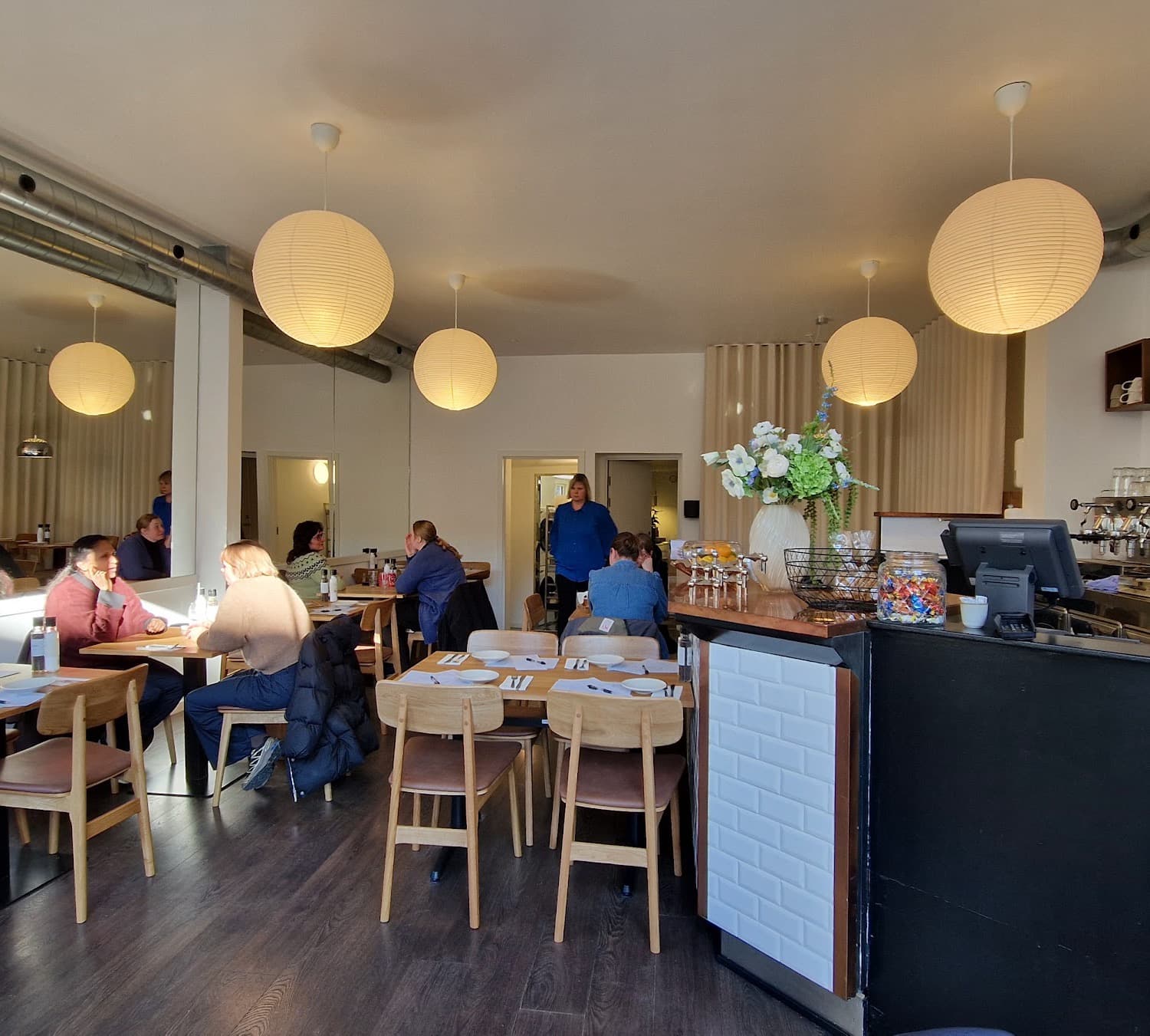 Kaffebaren hos MUNN med espressomaskiner, hvide papirlamper og egetræsborde